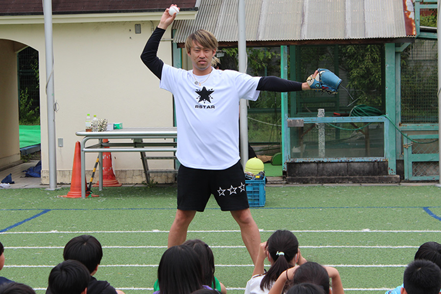 小学生にボールの投げ方を教える秋吉さん【写真：内田勝治】