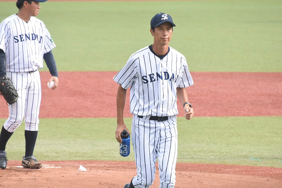 マウンドに給水ボトルを持参する仙台大・坪井俊樹コーチ【写真：川浪康太郎】