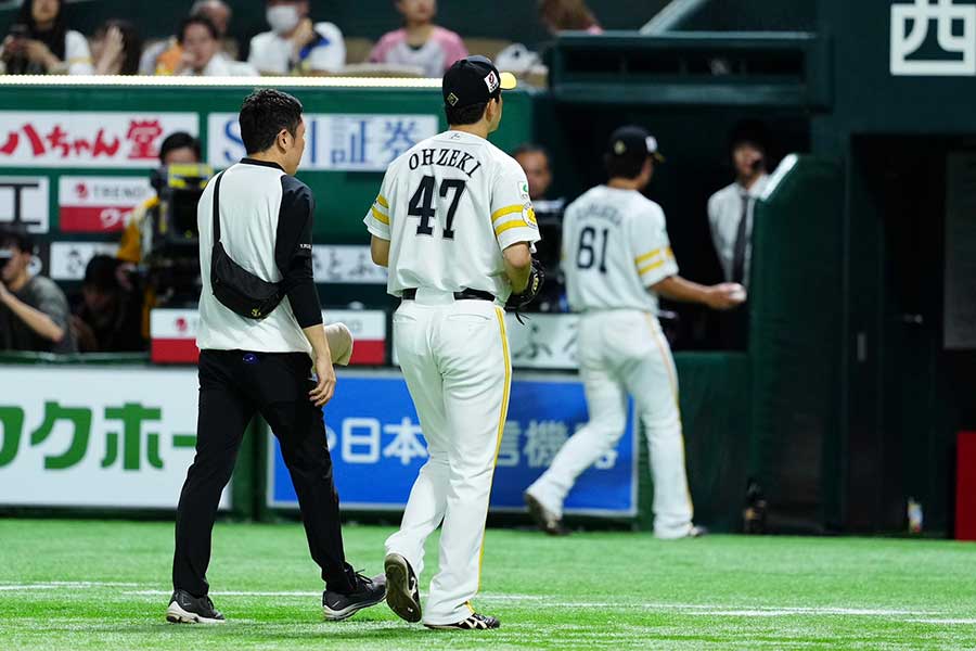 トレーナーとベンチへ下がるソフトバンク・大関友久（右）【写真：小林靖】