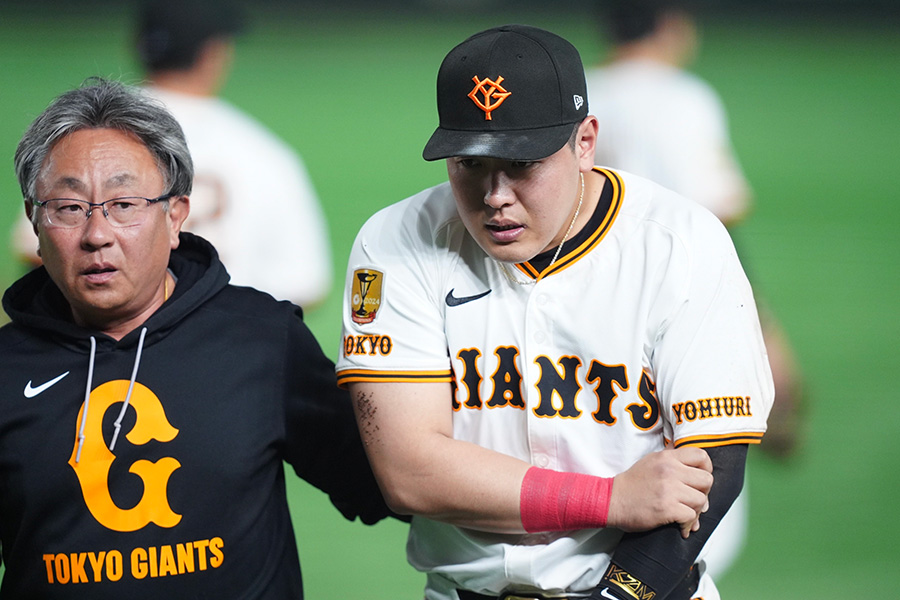 腕を抑えベンチに戻る巨人・岡本和真【写真：矢口亨】
