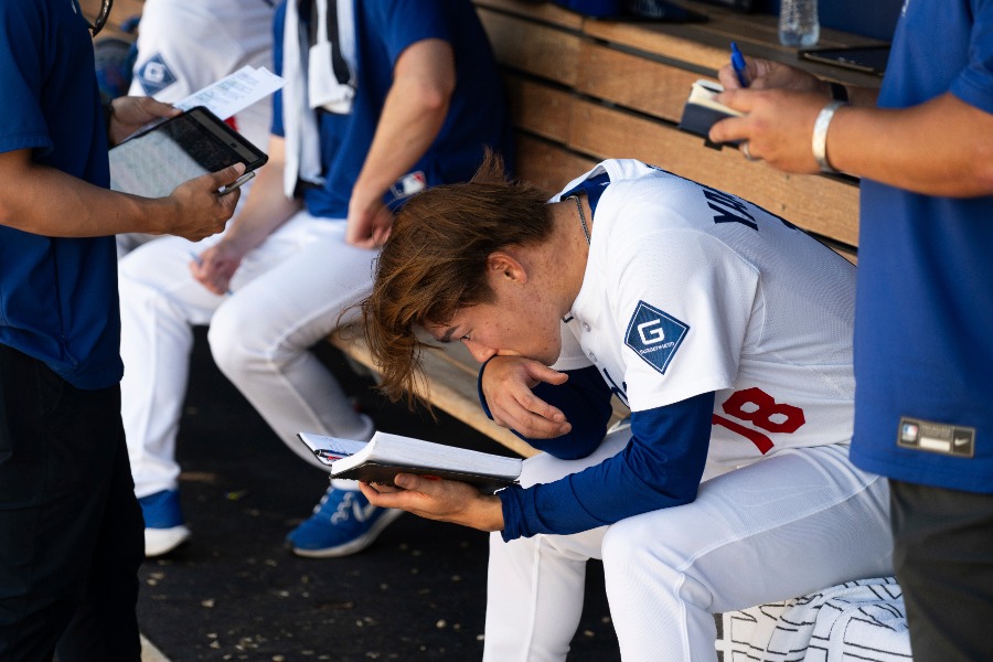 ベンチでノートを見るドジャース・山本由伸【写真:アフロ】