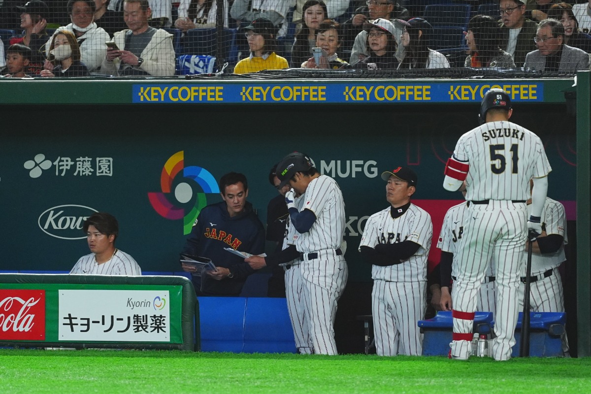 ベンチで資料を確認する大谷翔平（中央）【写真：小林靖】