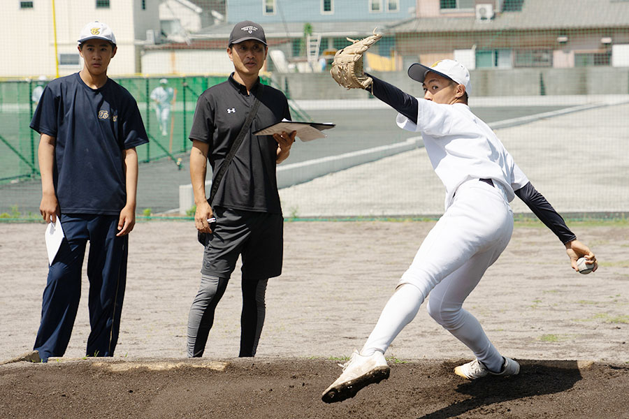 投球データを計測する志田宗大氏(中央)【写真:磯田健太郎】