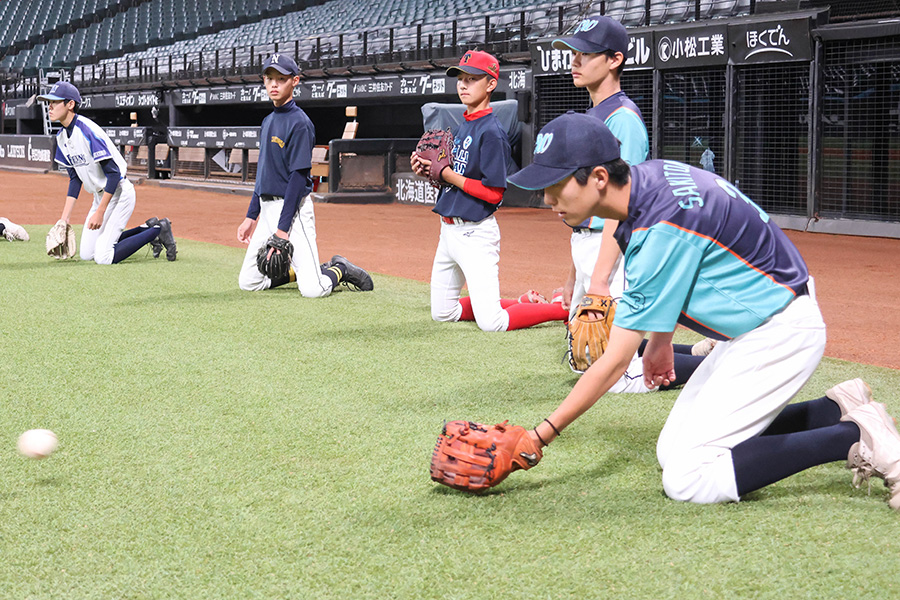 「膝立捕球」を実践する「FIGHTERS LEGENDS野球教室」の参加者たち【写真：石川加奈子】
